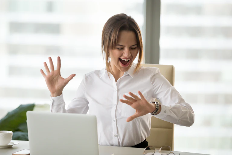 Woman in front of computer looking at watch.