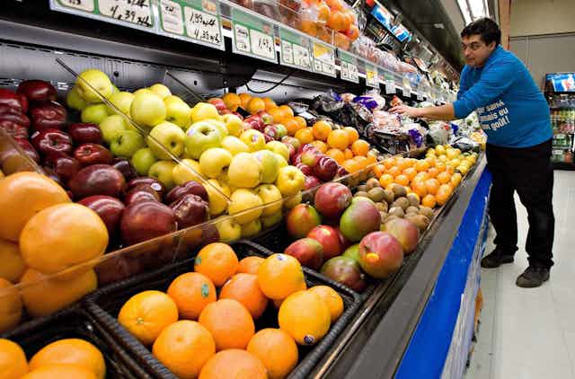 Un homme s'affaire dans la section des fruits et des légumes d'un supermarché