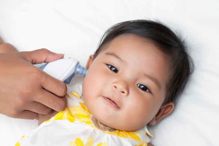A baby girl has her temperature taken with an aural thermometre