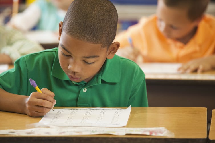 A Black boy works on a math problem in class.