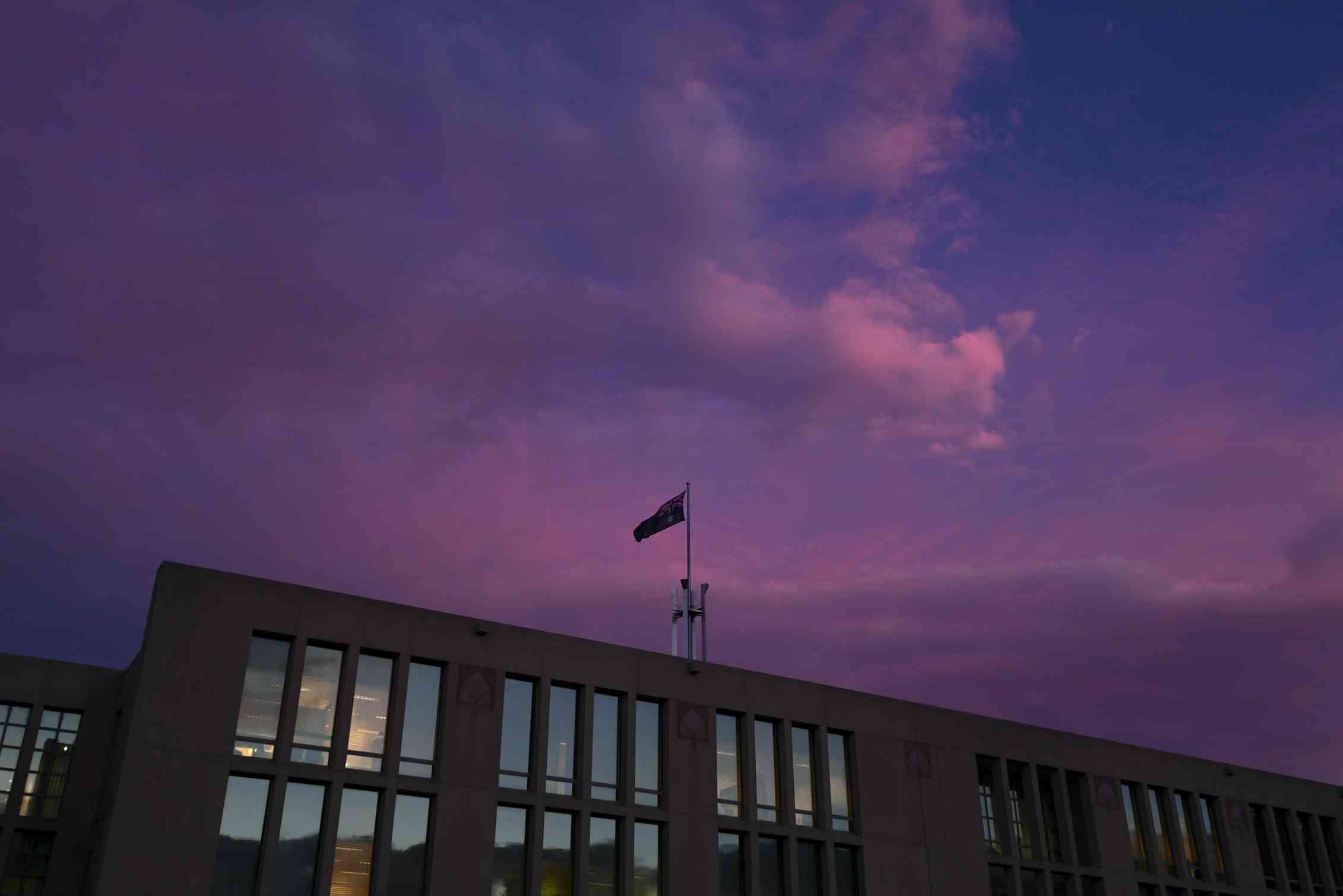 A pink sunset lights up then sky over Parliament House in Canberra.