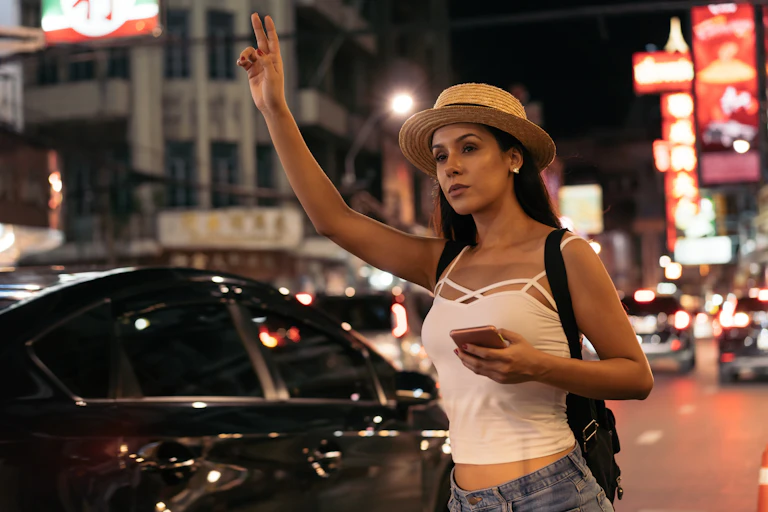 Young woman holding phone hailing ride.