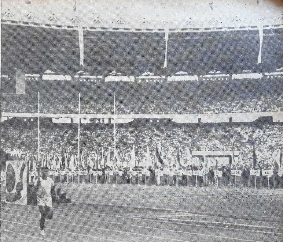 Black and white picture of a man carrying a torch in a stadium 
