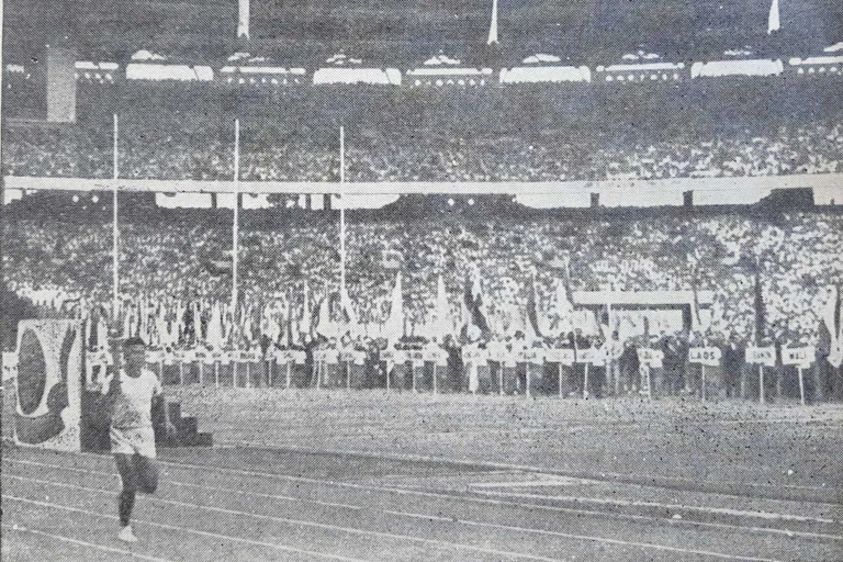 Black and white picture of a man carrying a torch in a stadium