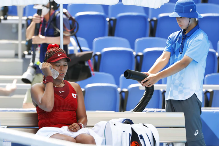 Tennis player Naomi Osaka holds an iced water bottle to her cheek during a cooling break