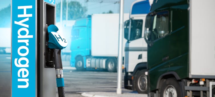 A hydrogen fuel pump at a service station with lorries in the background.