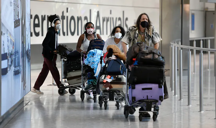 Travellers pushing luggage on trolleys at an airport