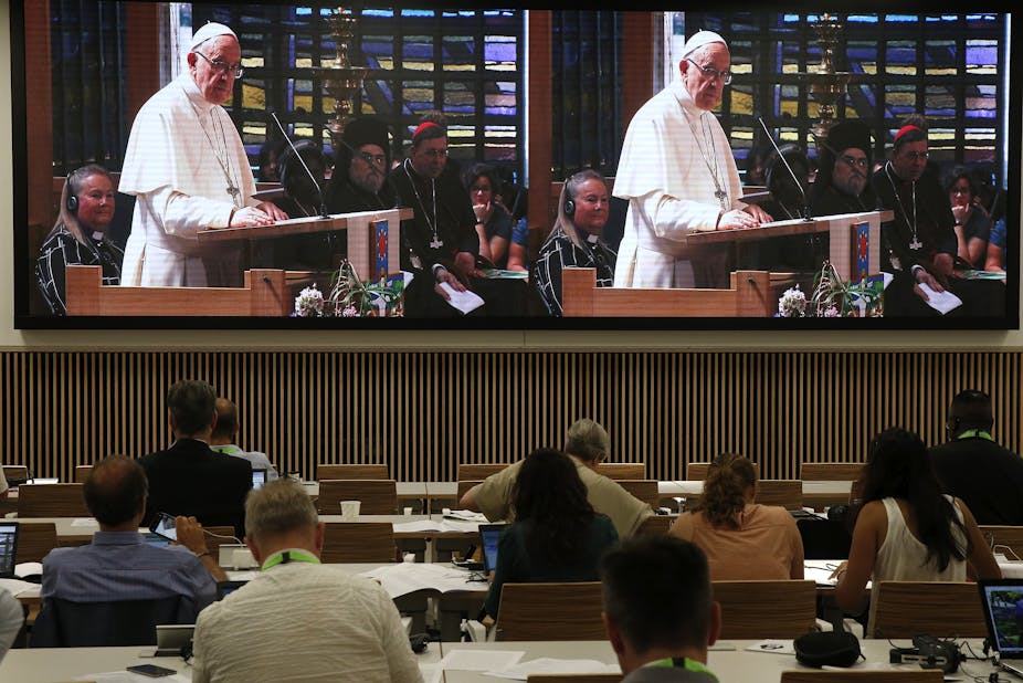 Journalists watch on a big screen as Pope Francis addresses the World Council of Churches.
