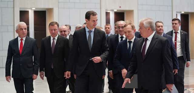 A group of men in suits surround Syrian president, Bashar al-Assad, and Russian special envoy Alexander Lavrentiev at a meeting in Damascus, July 2021.
