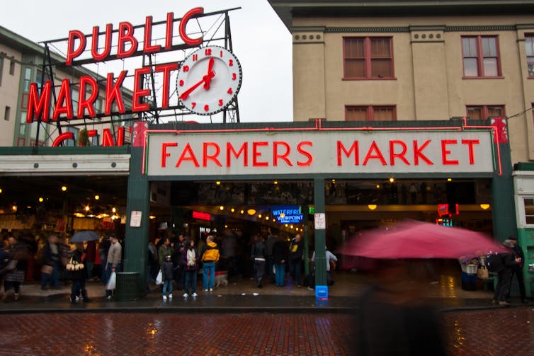 Shoppers enter market arcade on a rainy day.