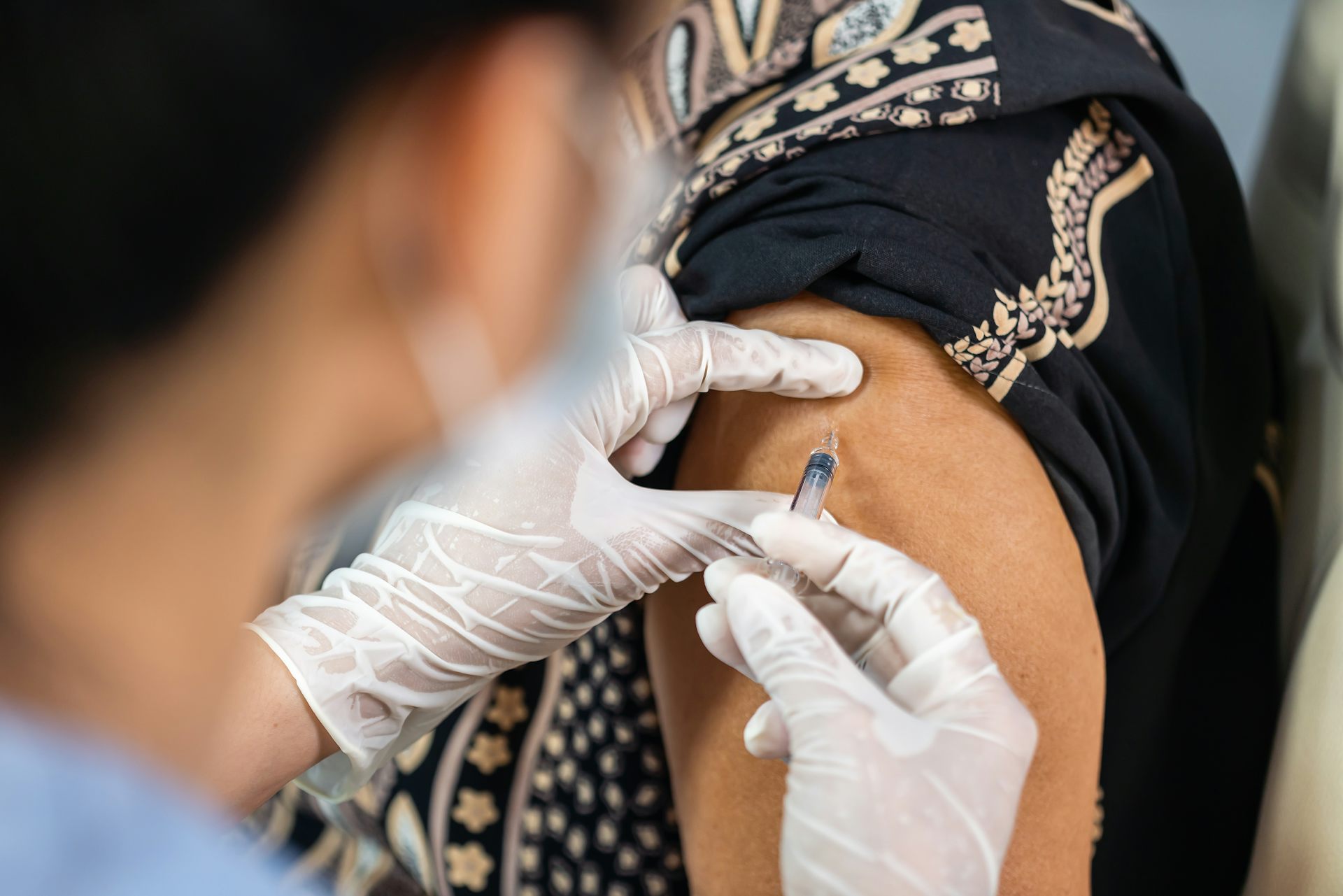 Un soignant vaccine une personne d'un certain âge, chez un rappel pourrait être utile.