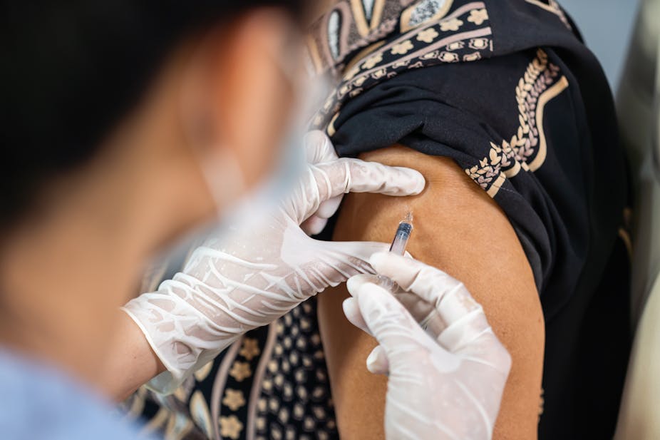 Un soignant vaccine une personne d'un certain âge, chez un rappel pourrait être utile.