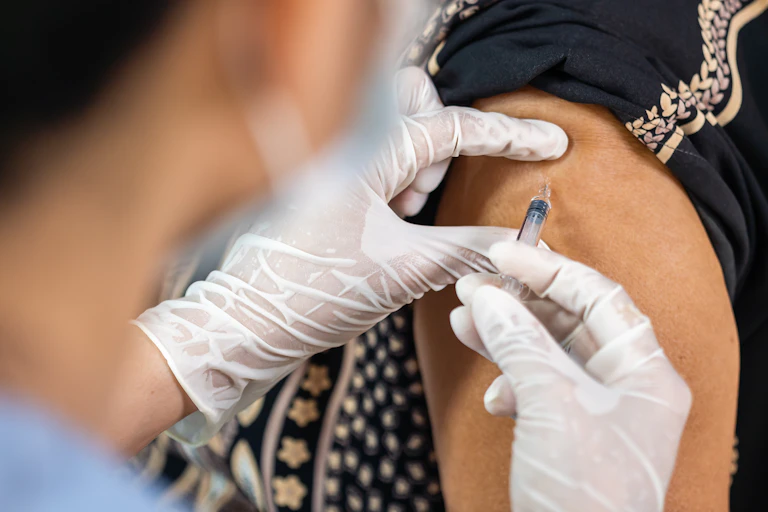 Un soignant vaccine une personne d'un certain âge, chez un rappel pourrait être utile.