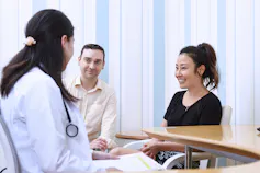 A medical professional sitting with a couple.