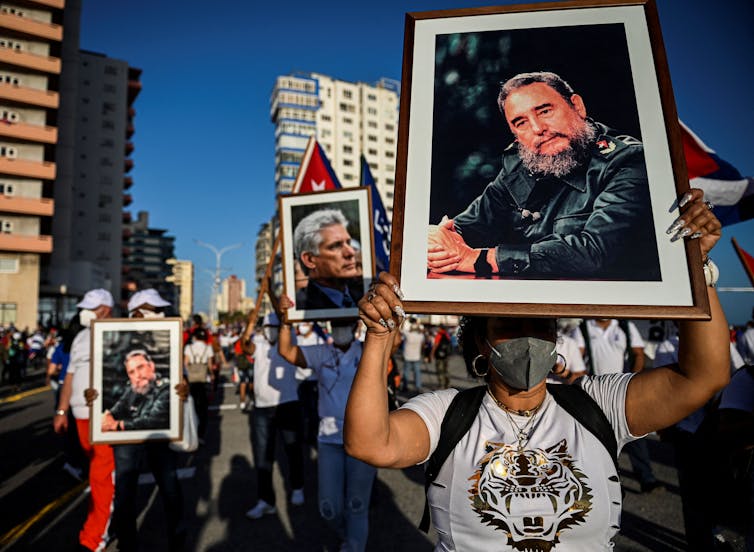 Marchers on street hold pictures of Cuban leaders