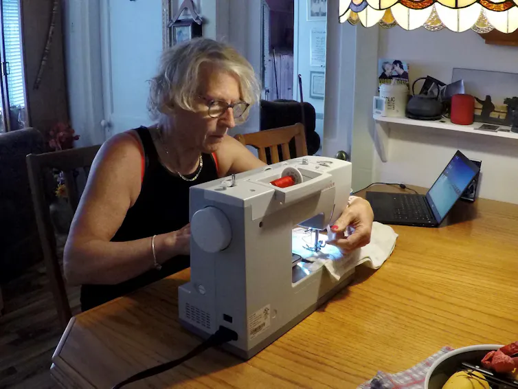 Une dame est installée devant une machine à coudre
