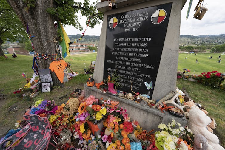A memorial is covered in toys, orange, flowers to commemorate those who died at IRS