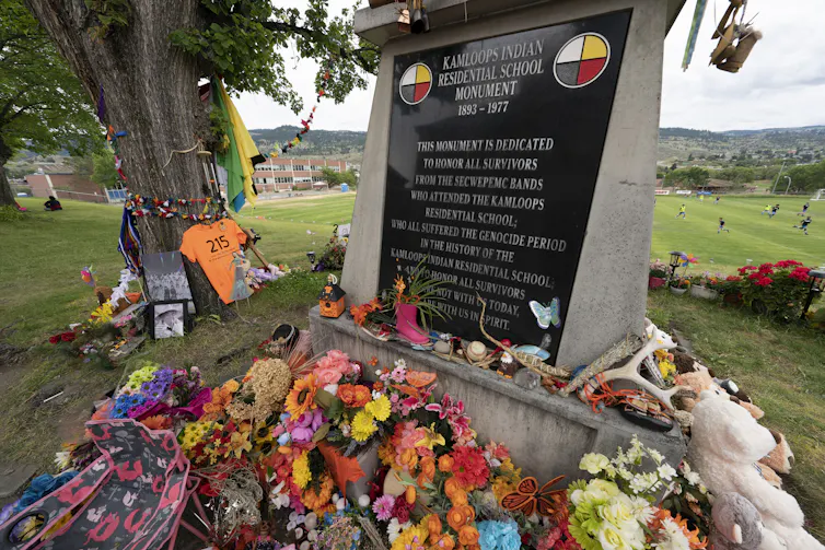 A memorial is covered in toys, orange, flowers to commemorate those who died at IRS