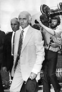 William ‘Billy’ McMahon walks in front of a media cameraman.