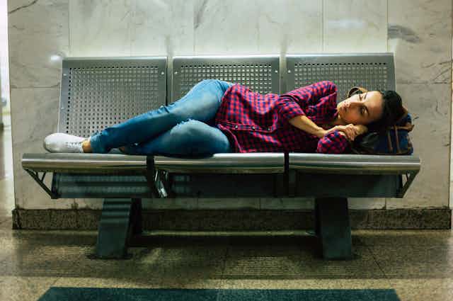 A woman lies on an indoor bench