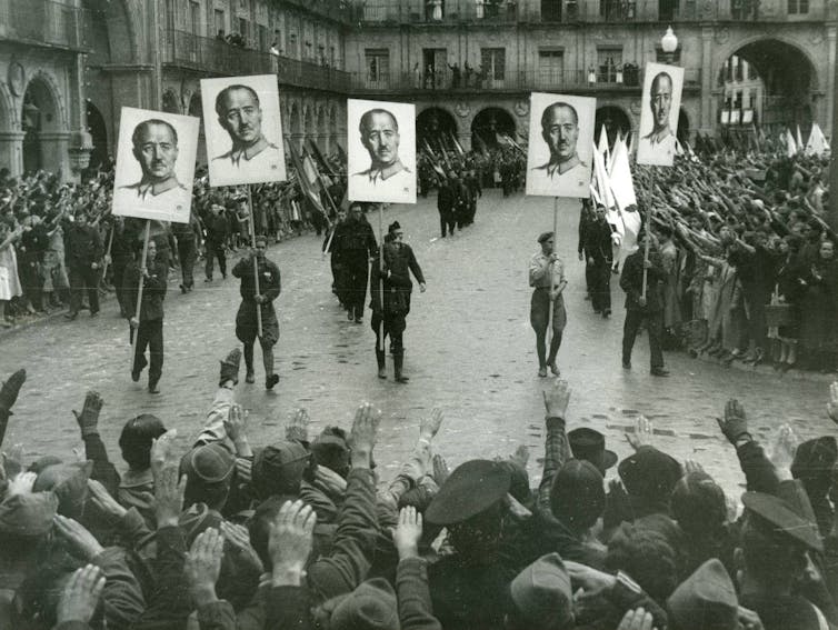 Francoist demonstration in Salamanca (1937) with the paraders carrying the portrait of Franco in banners and the populace pulling the Roman salute.