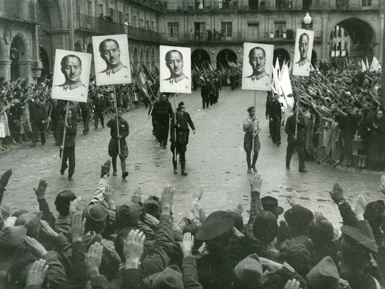 Francoist demonstration in Salamanca (1937) with the paraders carrying the portrait of Franco in banners and the populace pulling the Roman salute.