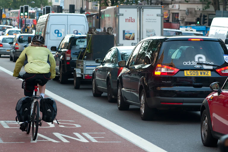 A cyclist rides down a bus lane next to a traffic jam of cars.