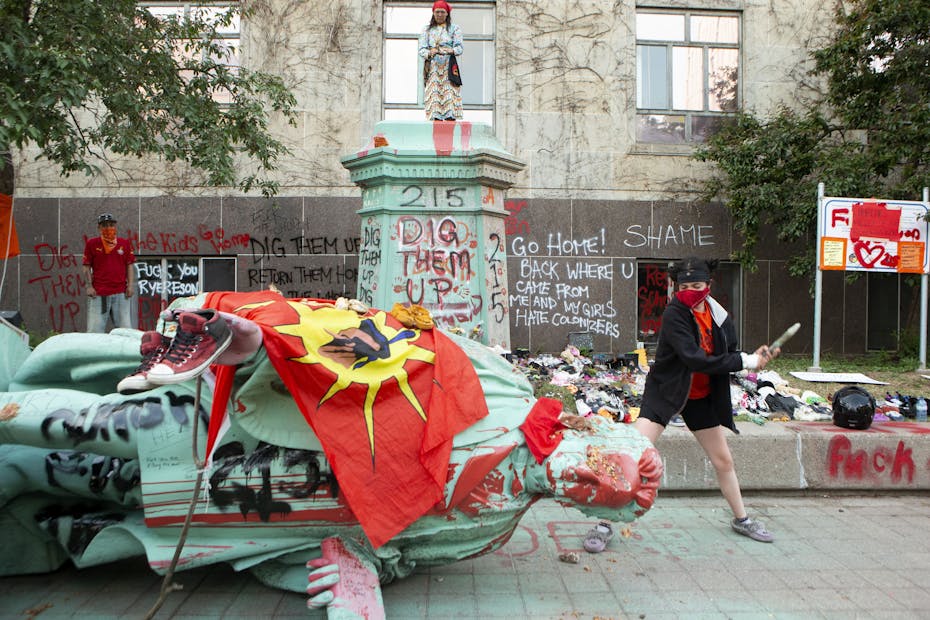 A protester hits the head of Egerton Ryerson's statue