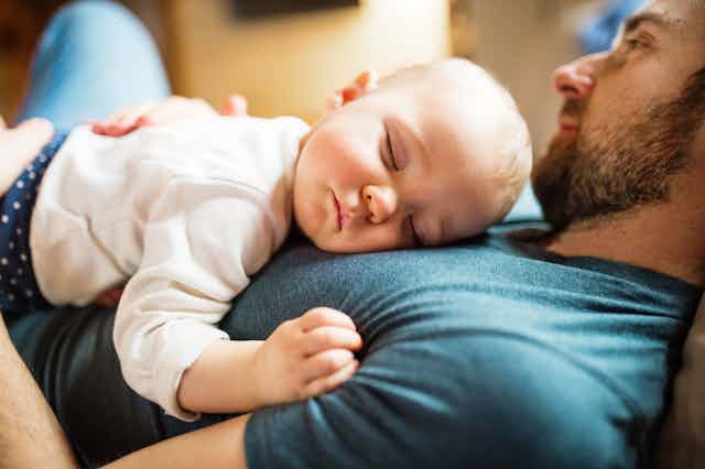 A baby asleep in a man's arms