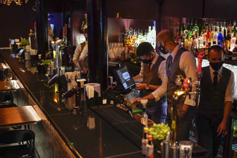 Men stand masked behind a bar