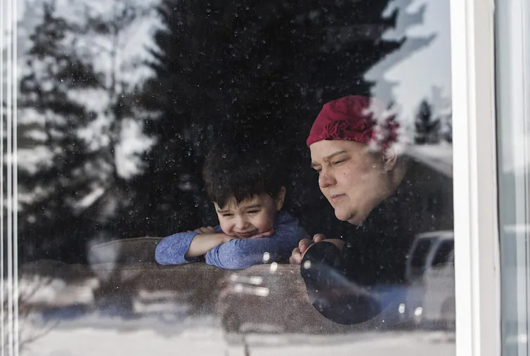 Woman stares out of a window with her son