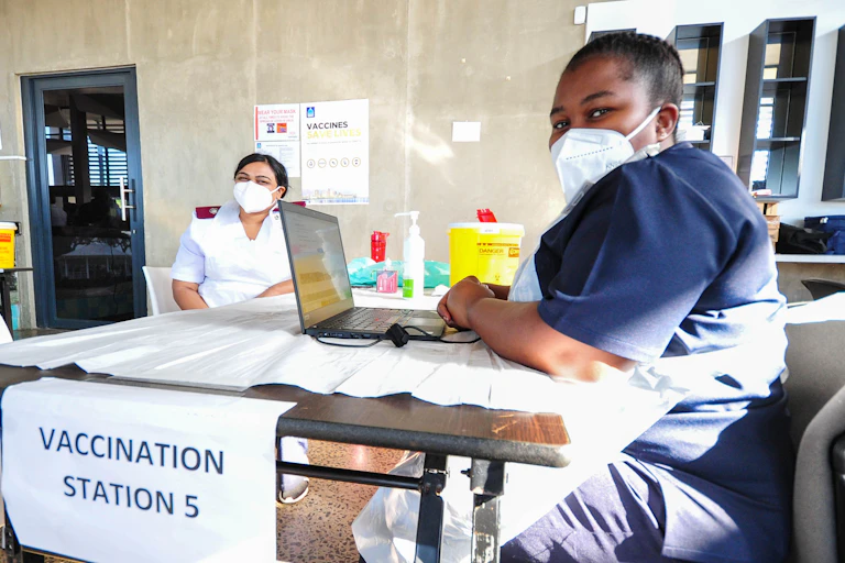 2 nurses wearing masks sitting at a desk
