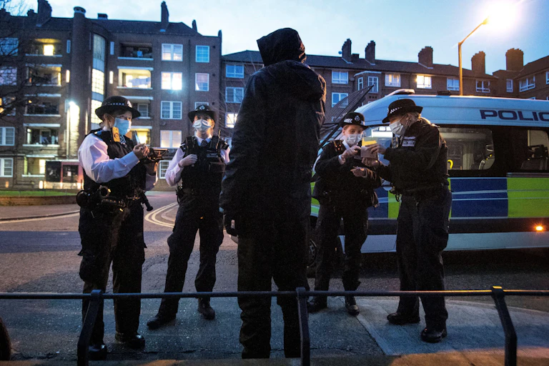 Police stop and search a man in Southwark, London.