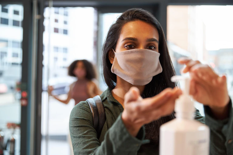 Woman using hand gel as she enters a shop