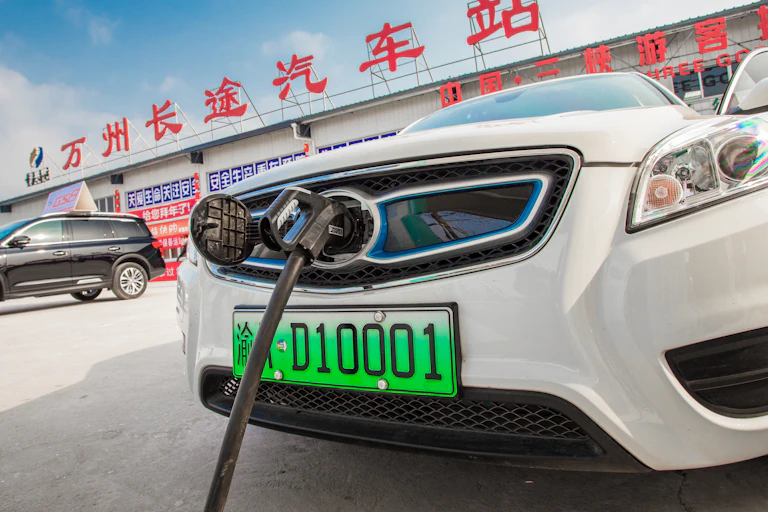 A white saloon car plugged into a charging point.