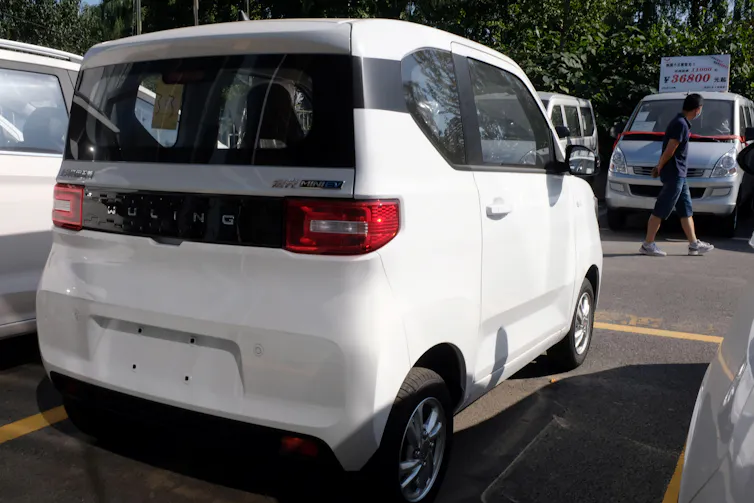 A small box-like car in a parking space.