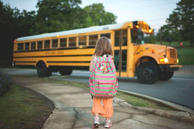 Girl with backpack walks to school bus