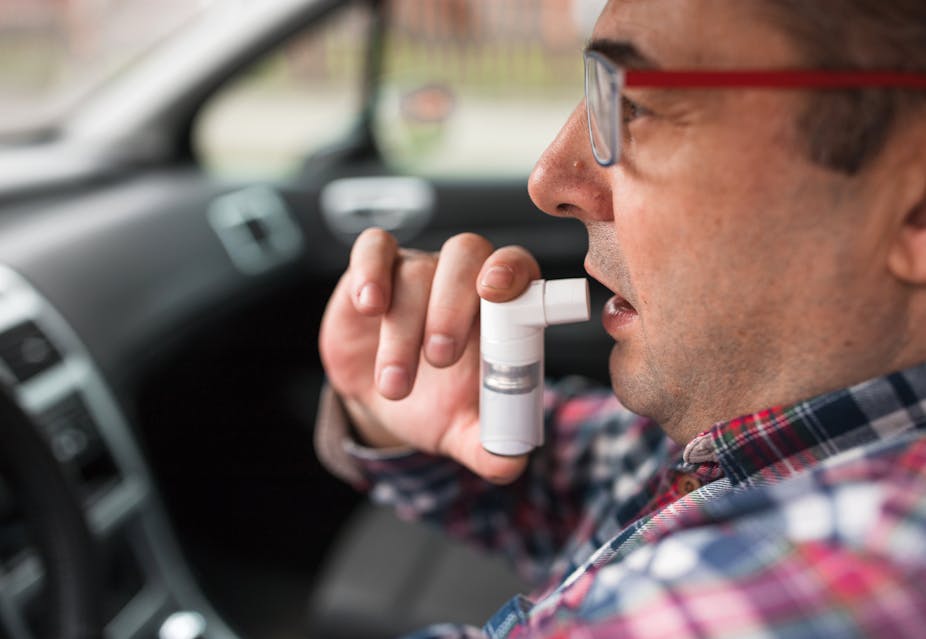 man about to use inhaler in the car