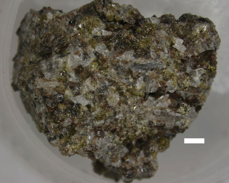 A blue-, white- and black-flecked rock in a white dish.