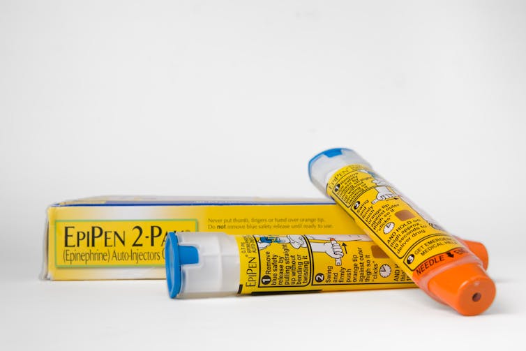Dos cápsulas de Epipen colocadas delante de una caja del medicamento.