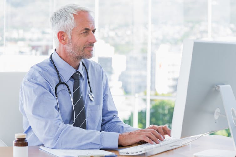 Male doctor types at his computer.