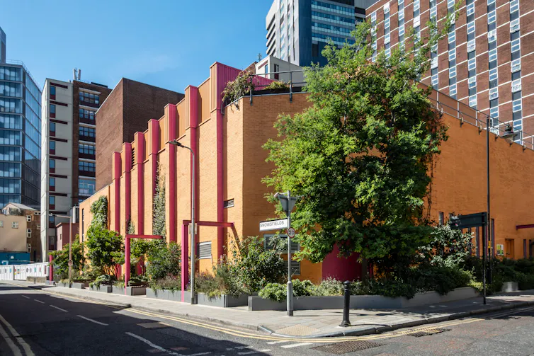 A tiny park with trees and bushes sits on the corner of a London street