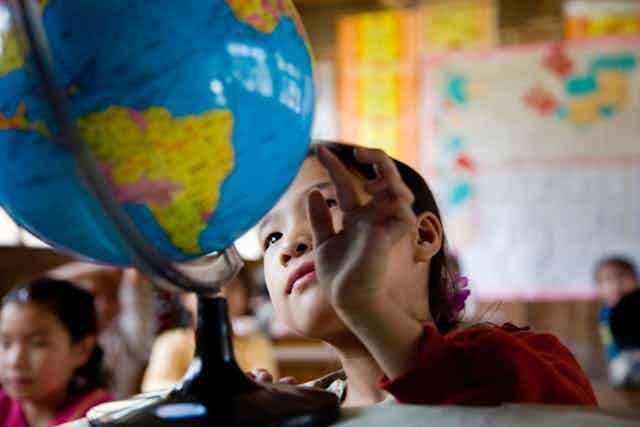 Una alumna observa una bola del mundo