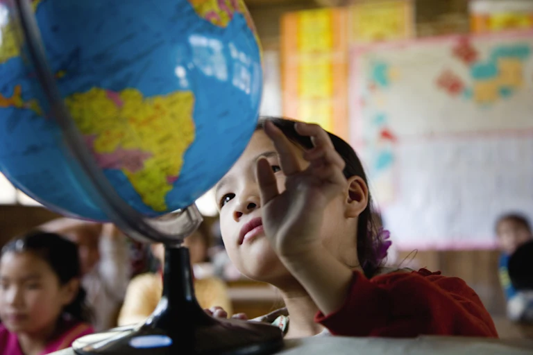 Una alumna observa una bola del mundo