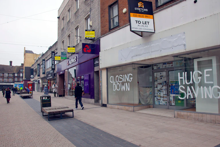A few pedestrians walk past high street retail spaces to let