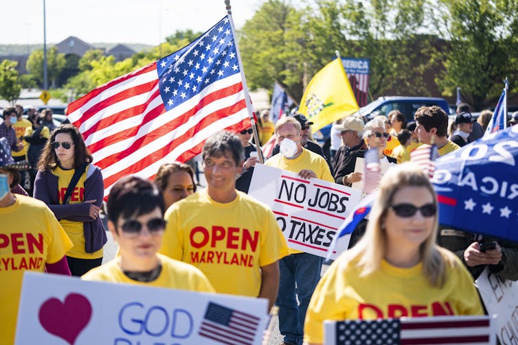 Protesters hold up signs calling for Maryland to be released from COVID restrictions.