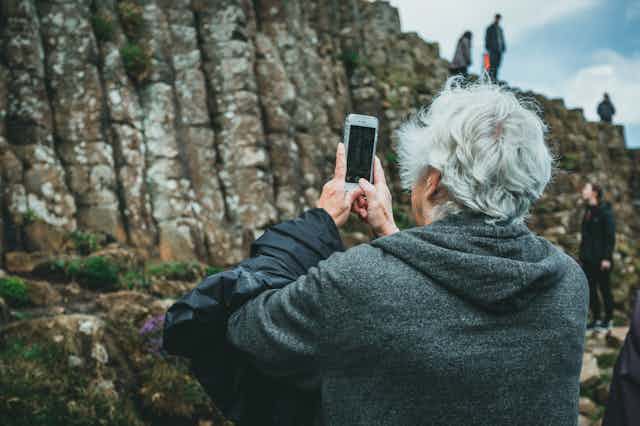 Un homme âgé prend en photo un rocher avec son cellulaire