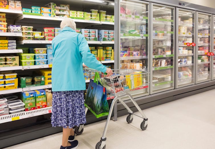 Lone elderly woman shops in a supermarket.