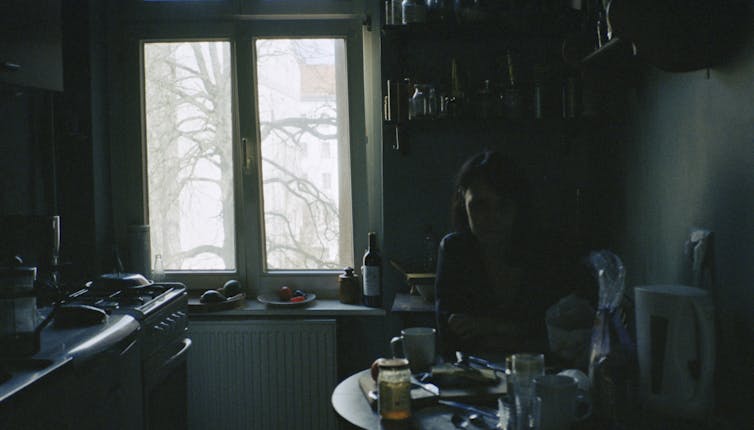 woman sitting in dark kitchen