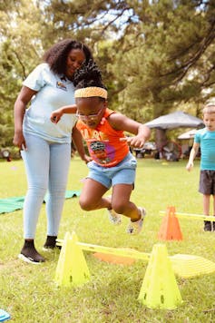 Child jumps over obstacle course in park